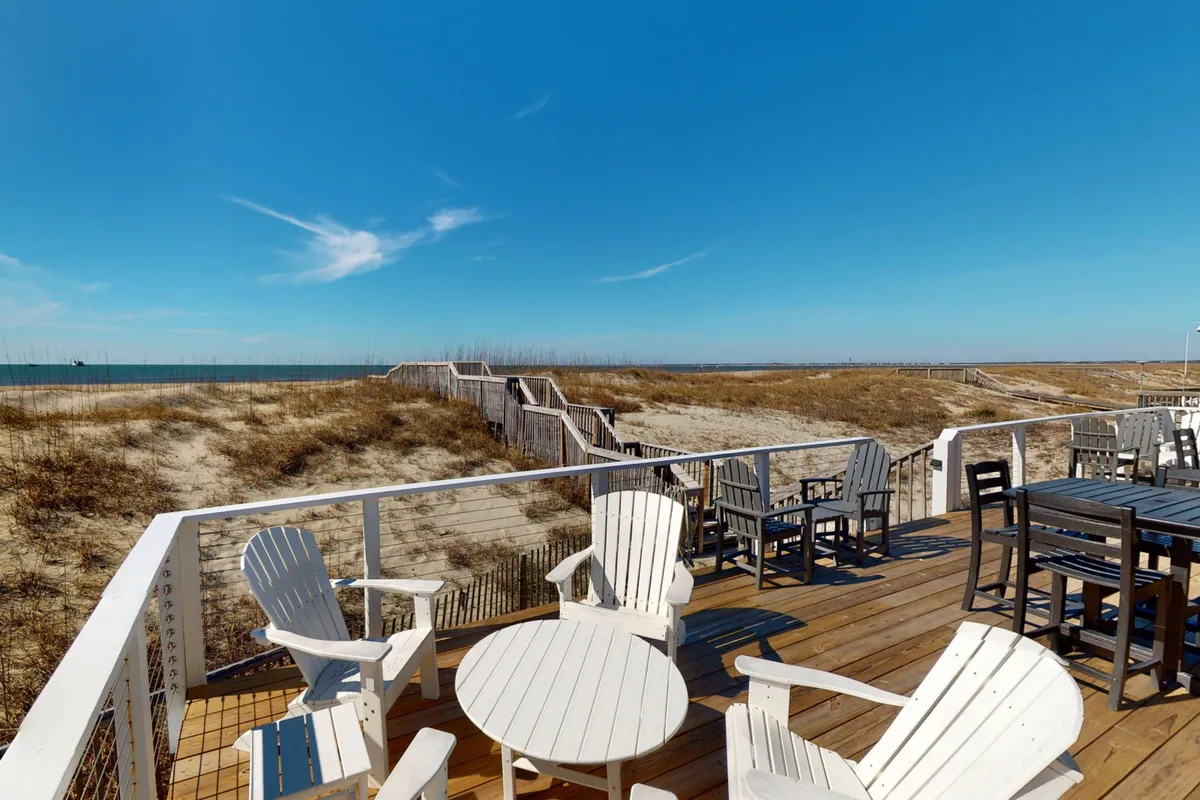 A tranquil, inviting deck sits right above the beachfront, with comfortable outdoor seating and panoramic ocean views stretching to the horizon. The space feels perfect for socializing, dining, or simply relaxing with loved ones while watching the sunrise or sunset.