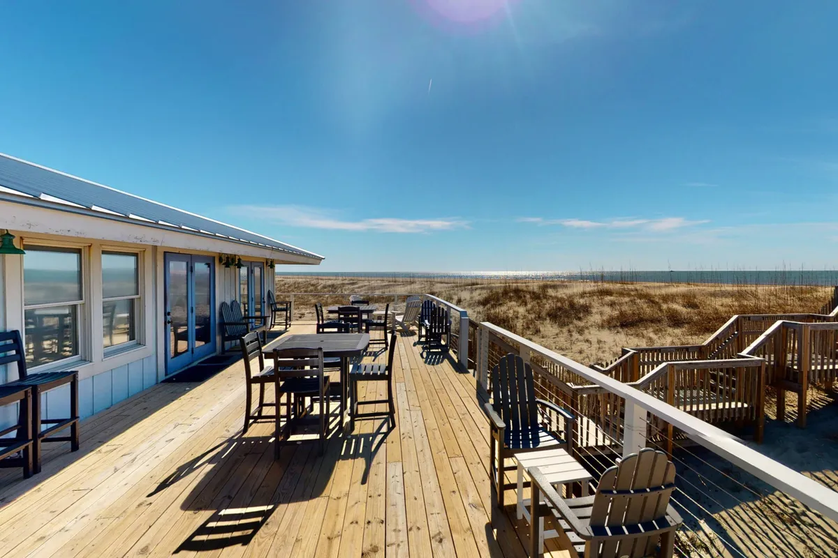 The image spotlights a spacious wooden deck equipped with comfortable outdoor seating, all facing a sweeping ocean view. The tranquil setting is ideal for group dining, morning coffee, or evening barbecues, reinforcing the property’s appeal for reunions and retreats.